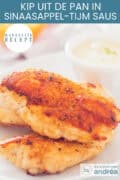 Een deel van een bord met twee gebakken kipfilet met een sinaasappel tijm saus ernaast.