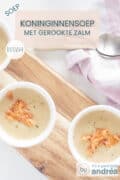 Twee witte kommen op een houten plank gevuld met gebonden kippensoep en zalm. Een tekst bovenin: soep, koninginnensoep met gerookte zalm, makkelijk recept.