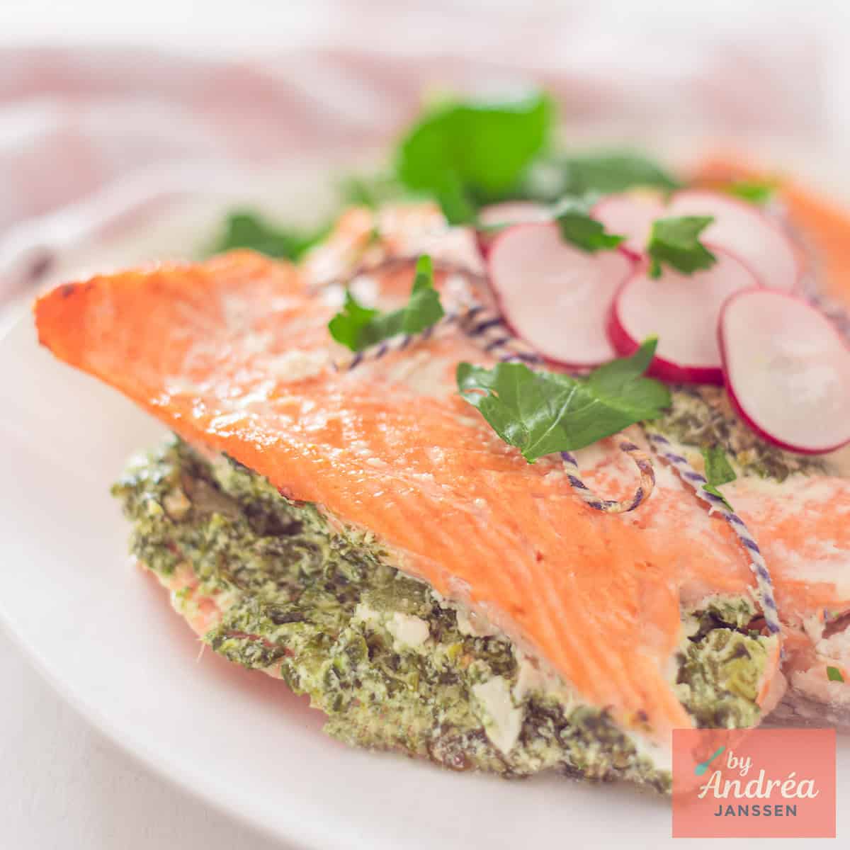 Een vierkante foto van een deel van een zalmfilet gevuld met een romige spinazievulling