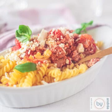 Een vierkante foto met een wit ovenschaaltje met pasta met feta, tonijn en tomaat