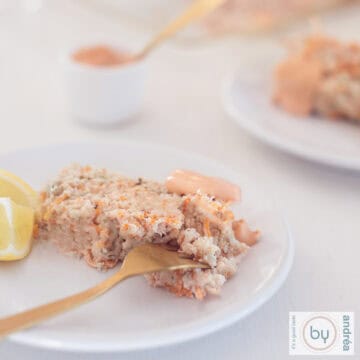 Een vierkante foto met twee bordjes met een plakje visterrine met kabeljauw en zalm. Whiskysaus in de achtergrond