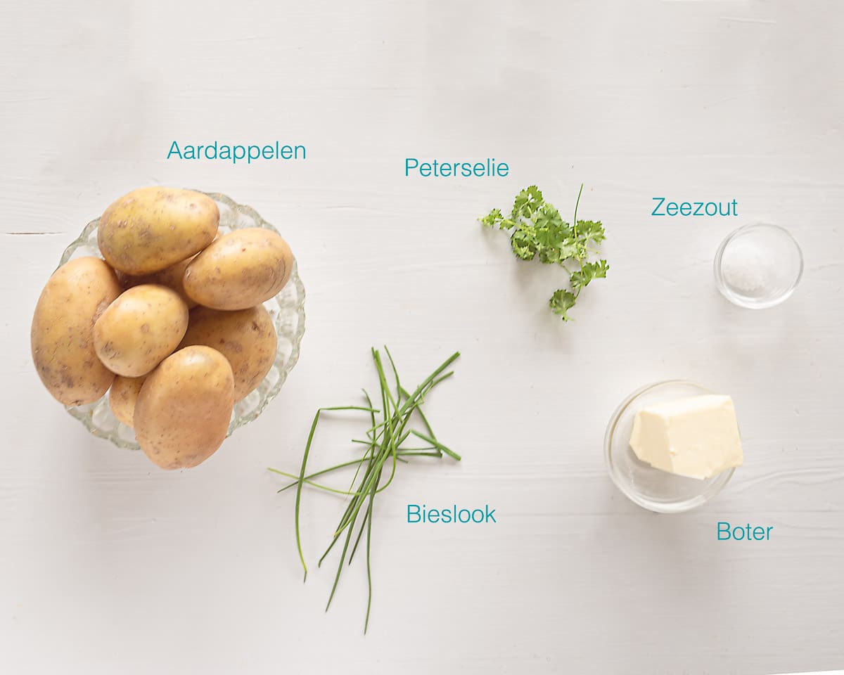 Ingrediënten gekookte aardappels met Peterselie boter op een witte plank met een ingredienten beschrijving in tekst