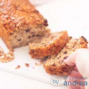 A square photo showing part of a granola cake, two slices cut off. A hand grabs the front slice