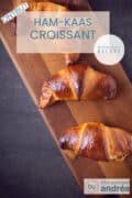 Een foto van bovenaf van croissants op een houten plank. Een text overlay ham-kaas croissant, ontbijt, makkelijk recept.