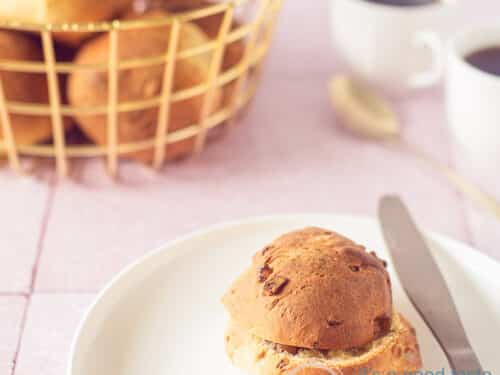 Een bord met een walnootbroodje met sinaasappelbroodjes met walnoten in de achtergrond in een mand.