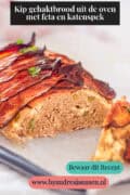Een deel van een kipgehaktbrood dat is opengesneden waardoor je de binnenkant ziet. Een tekst bovenin: kip gehaktbrood uit de oven met feta en katenspek