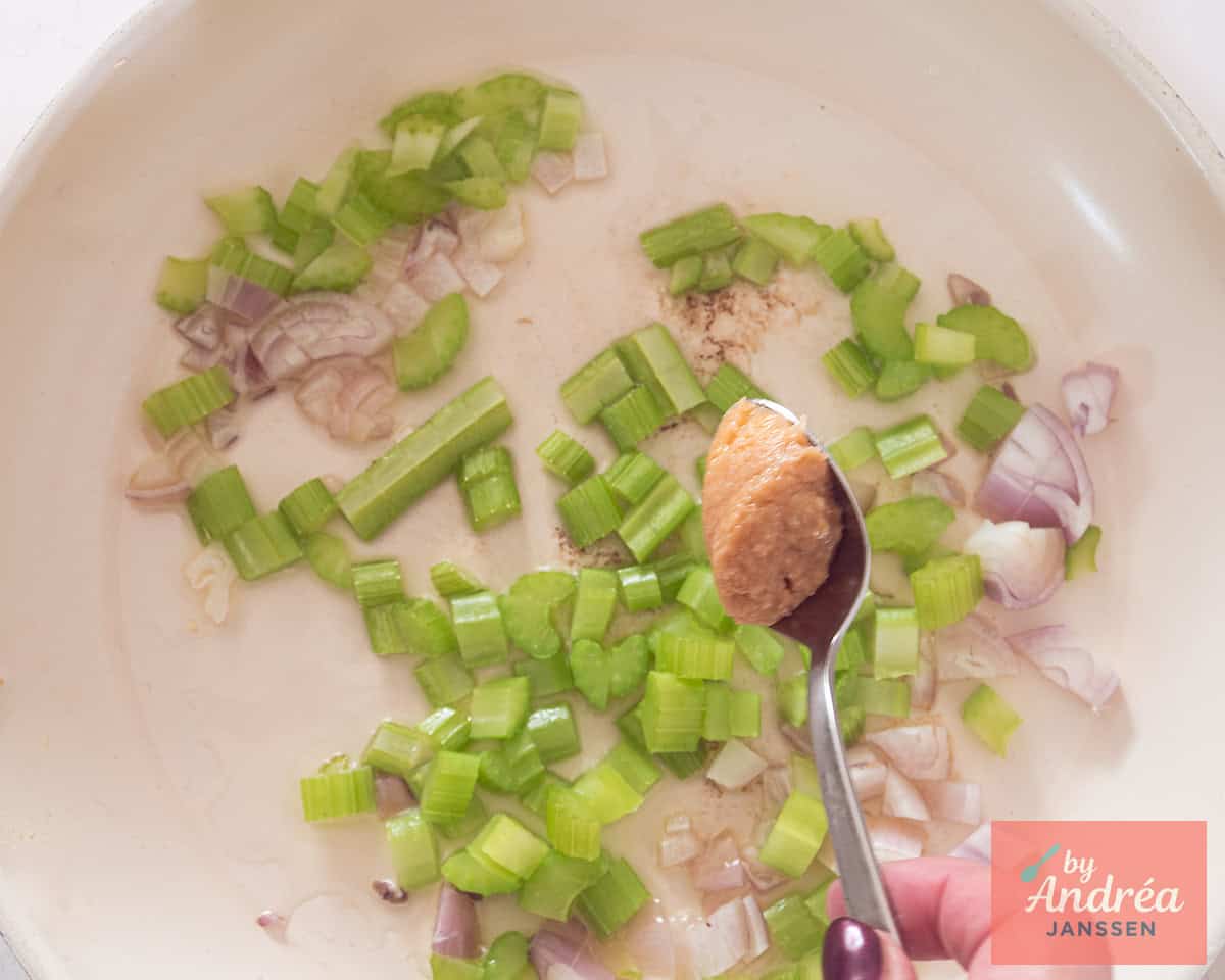 Bleekselderij en sjalotje wordt met knoflook in een koekenpan aangebakken.