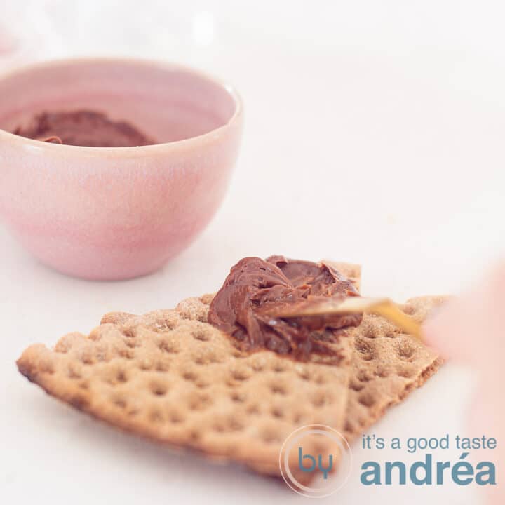 A person is spreading chocolate butter on a cracker.