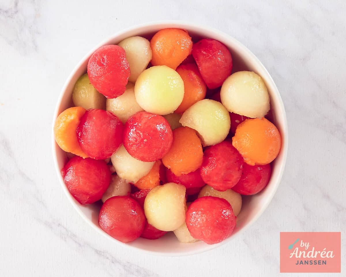 A photo from above with a bowl full of melon balls of three types