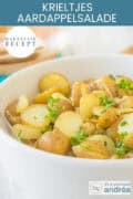 Een witte schaal gevuld met krieltjes en kruiden. Een tekst bovenin: makkelijk recept, krieltjes aardappelsalade
