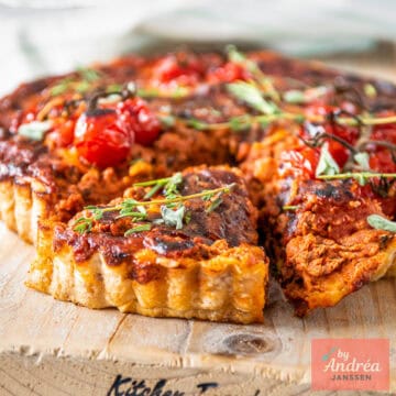 Een vierkante foto met bolognese quiche met een part eruit gesneden.