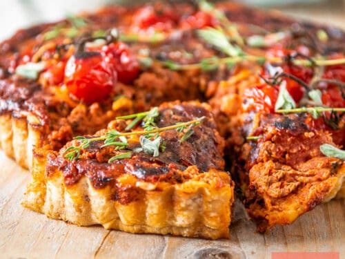 Een vierkante foto met bolognese quiche met een part eruit gesneden.