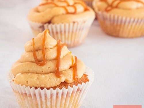 Een vierkante foto met vier cupcakes met frosting en een salted caramel topping.