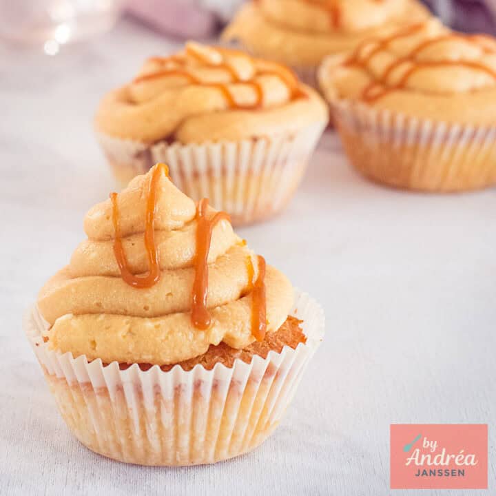 Een vierkante foto met vier cupcakes met frosting en een salted caramel topping.