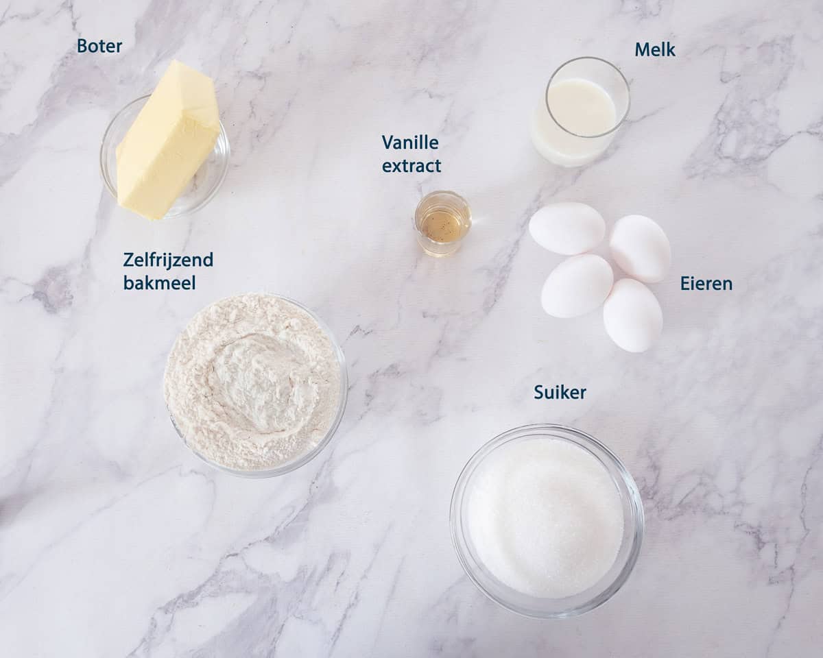 Ingredienten vanille cupcakes op een wit marmeren ondergrond met tekst beschrijving.