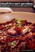 Close-up van een lepel met een stuk stoofvlees in glanzende donkerbruine saus, boven een kom stoofvlees met speculaas uit de slowcooker. Er liggen wat groene kruiden op. Bovenin staat de tekst "Stoofvlees met speculaas uit de slowcooker".