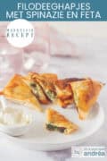 Een deel van een wit bord met hapjes van filodeeg, spinazie en feta. Een dip ervoor en een half hapje waardoor je de vulling kunt zien. Erboven een tekst: makkelijk recept, filodeeg hapjes met spinazie en feta