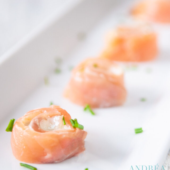 Vier zalm roomkaas rondjes op een witte schaal bestrooit met bieslook