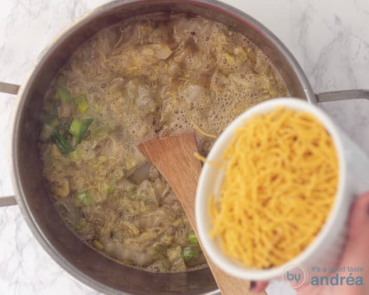 Een kom vermicelli die wordt toegevoegd aan een koolprei soep.