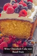 Een deel van een witte chocolade cake (de binnenkant is zichtbaar) met witte chocolade botercrème en vers fruit topping. Een tekst: witte chocolade cake met rood fruit.