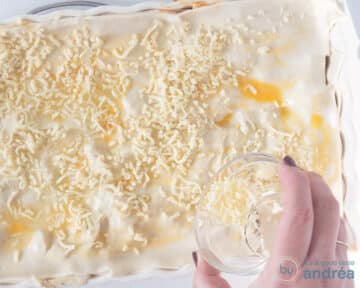 An oven dish covered with puff pastry, brushed with egg and sprinkled with grated cheese.