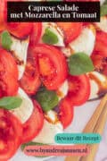 Schijfjes tomaat, mozzarella, basilicum en een drizzle van balsamico op een wit bord. Een tekst: caprese salade met mozzarella en tomaat