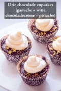Een deel van een taartplateau met vier cupcakes met ganache, witte chocolade crème en pistache. Een tekst bovenin: Drie chocolade cupcakes (ganache + witte chocoladecrème + pistache)
