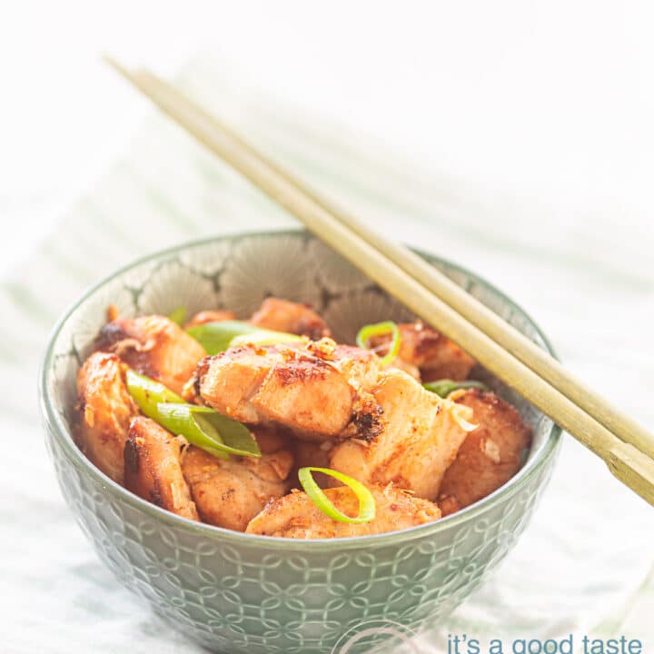 Een groen kommetje met kip met 4 smaken gekruid. Twee chopsticks liggen erboven op. Het kommetje staat op een groen wit gestreepte handdoek