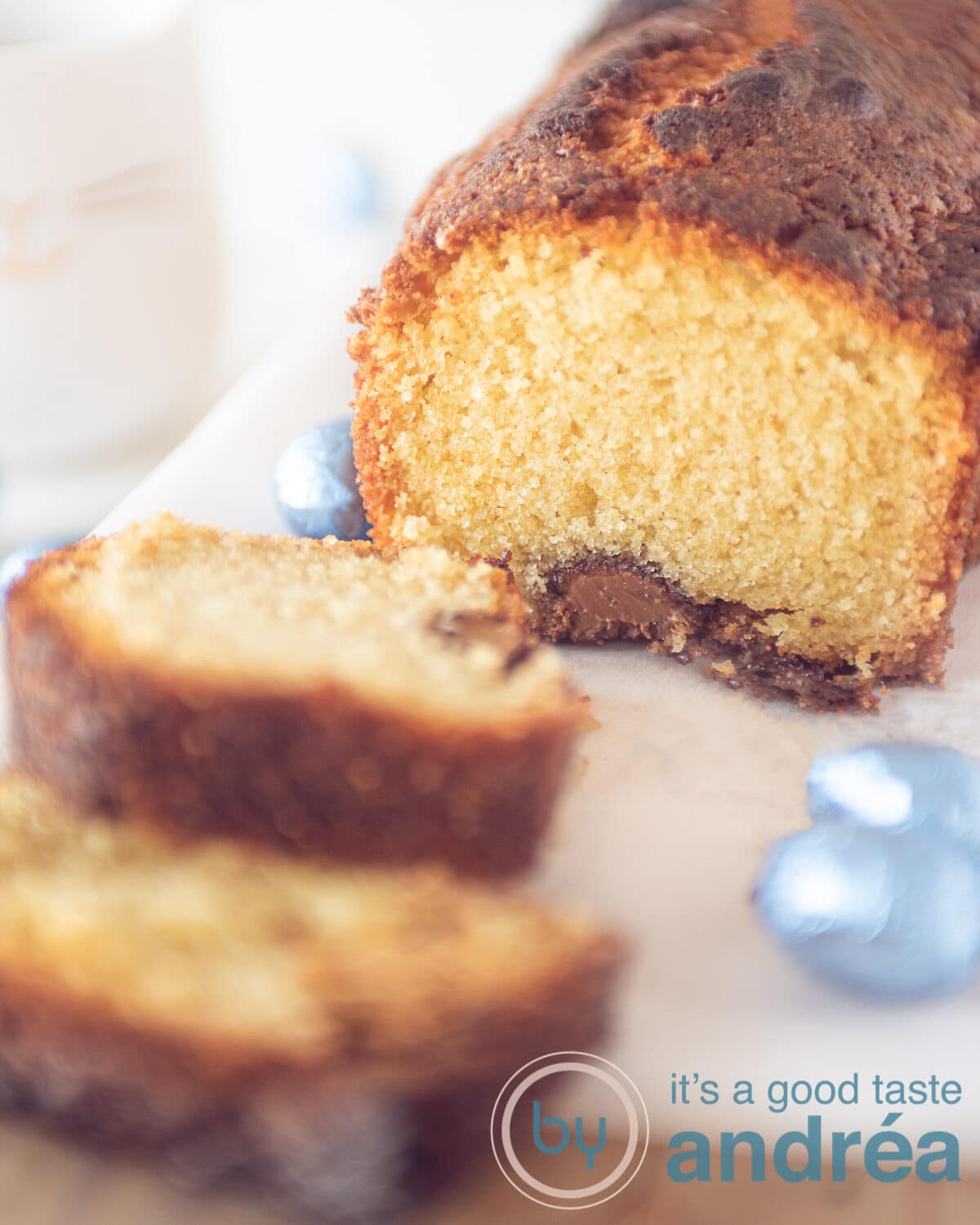 Een foto van een cake gevuld met paaseitjes op een witte plank. Een kopje thee in de linker achterzijde