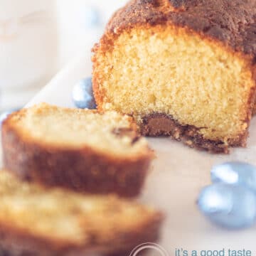 Een foto van een cake gevuld met paaseitjes op een witte plank. Een kopje thee in de linker achterzijde