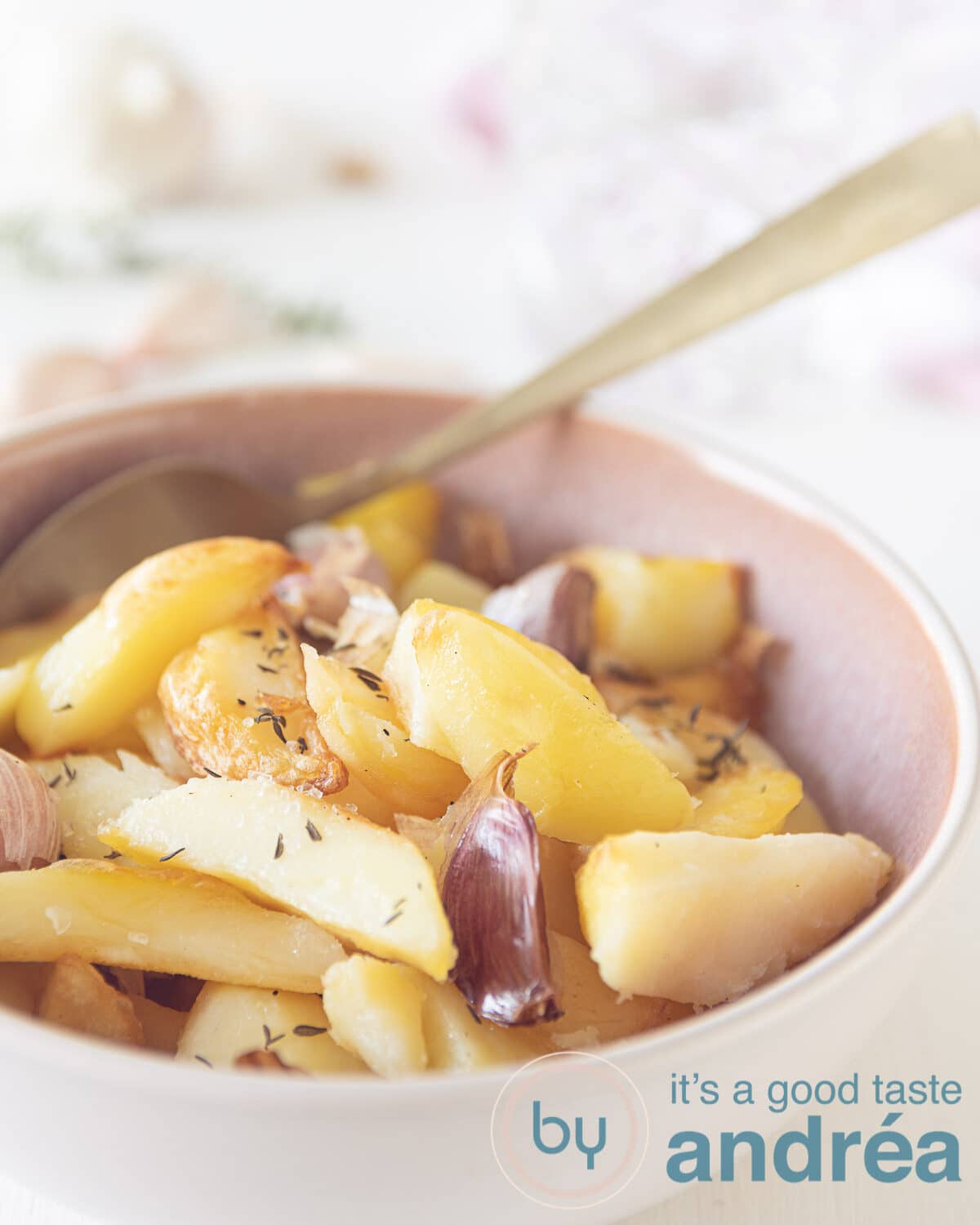 oven gebakken aardappelen met knoflook en tijm in een roze schaaltje.