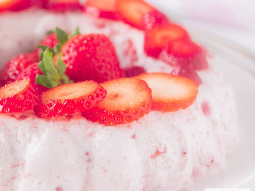 Een vierkante foto met zelfgemaakte aardbeienbavarois met verse aardbeien.