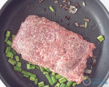Een koekenpan met ui, knoflook en bleekselderij, en rundergehakt.