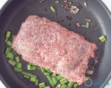 Een koekenpan met ui, knoflook en bleekselderij, en rundergehakt.