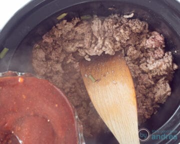 Een slowcooker met gehakt, daarop wordt de sloppy joe saus gegoten