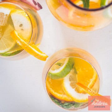 Een vierkante foto met twee glazen ijsthee met citrus en een karaf.