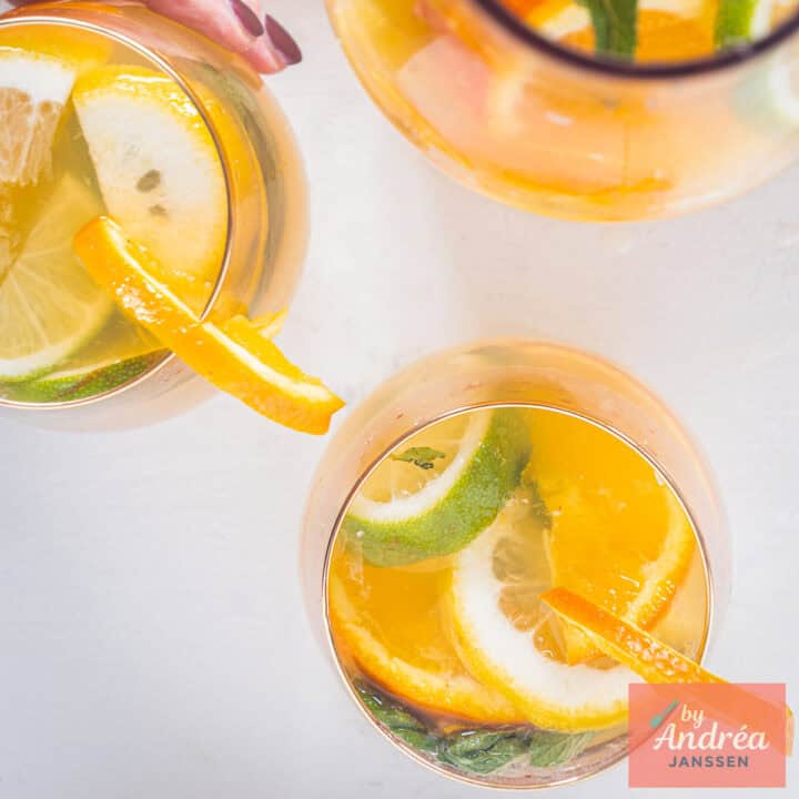 Een vierkante foto met twee glazen ijsthee met citrus en een karaf.