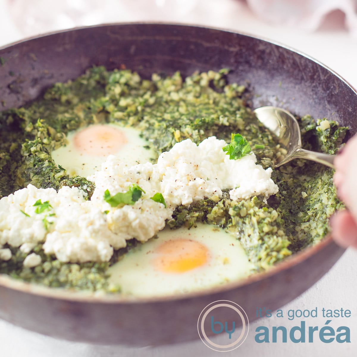 Een vierkante foto met een zwarte pan gevuld met een bloemkoolrijst, prei en spinazie schotel met ei en cottage cheese.