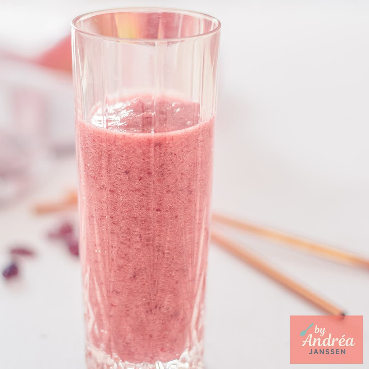 Een vierkante foto met een glas appel cranbery smoothie