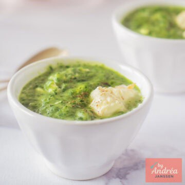 Een vierkante foto met twee kommen met rucola spinazie soep met creme fraiche.