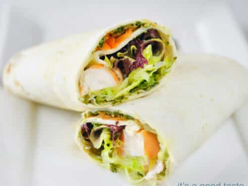 a square photo with two wraps filled with smoked chicken, salad, carrots and cucumber