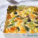 Een vierkante foto met een witte schaal gevuld met een broccoli frittata met Mozzarella. Een lepel ligt er boven