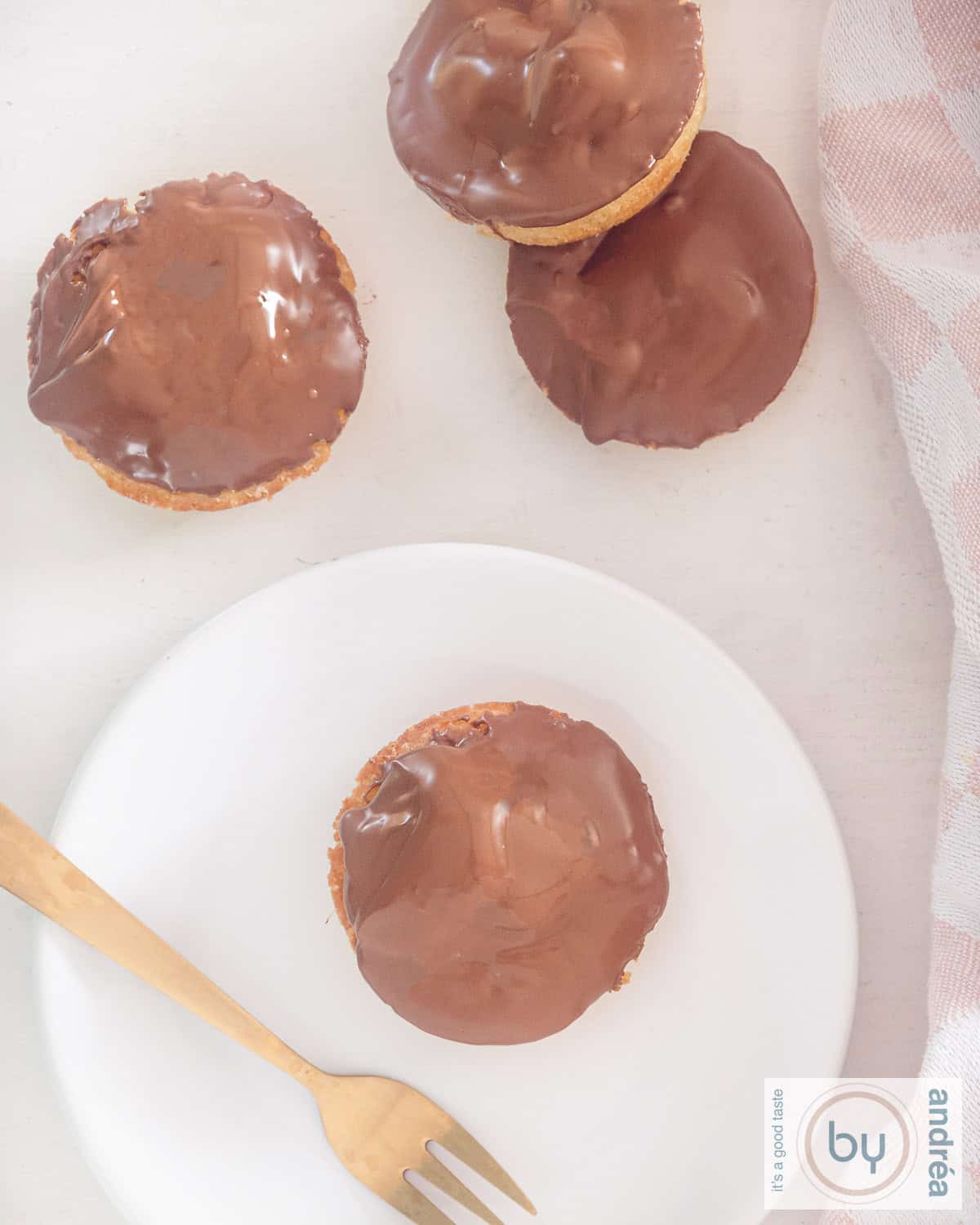 Een foto van bovenaf van Twix cupcakes. Een cupcake ligt op een wit bord met een gouden vork ernaast. Drie cupcakes liggen erboven