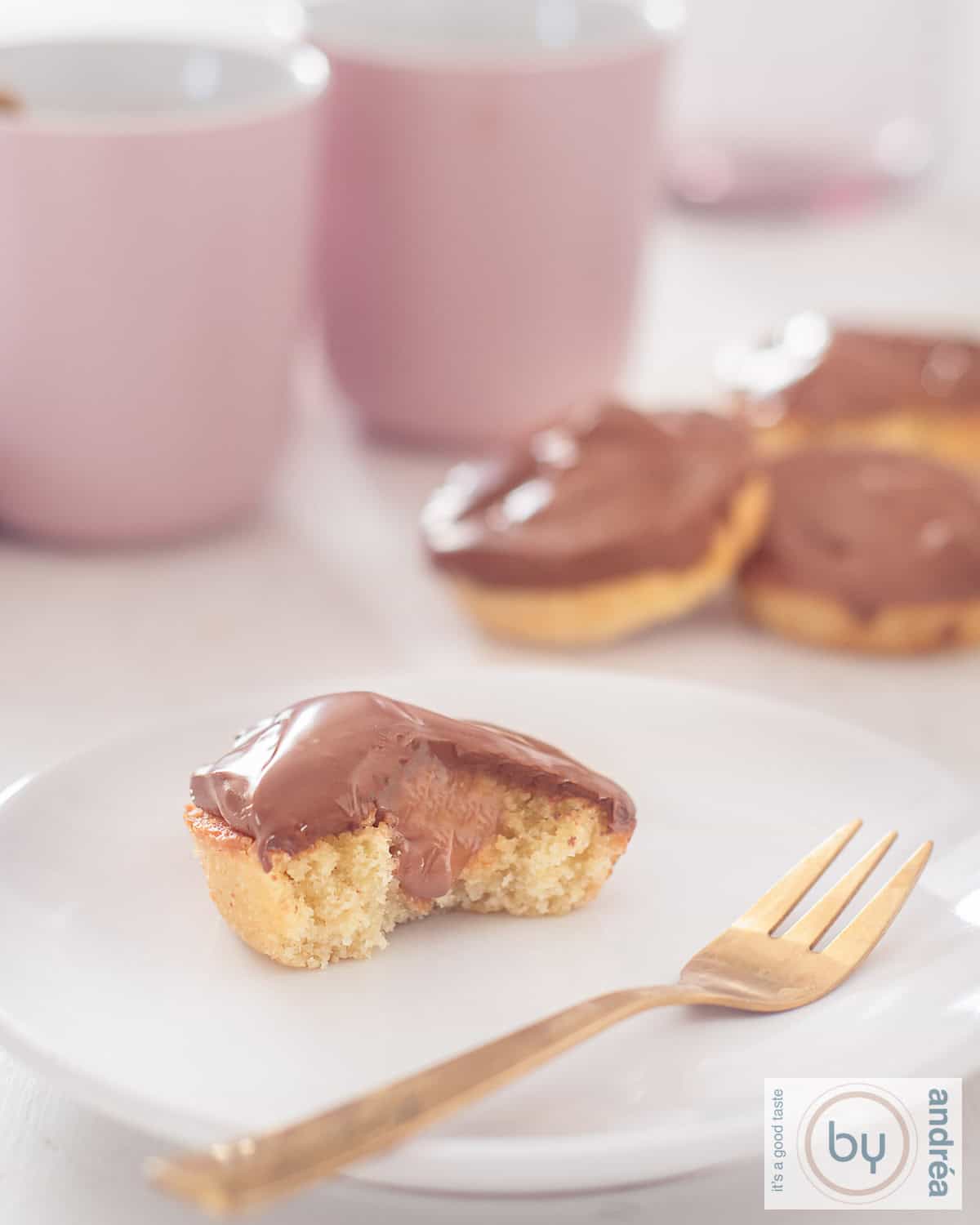 Een hoogtefoto met een bord met een halve Twix cupcake waar de cake, karamel en chocoladelaag goed zichtbaar is. In de achtergrond een stapeltje Twix Cupcakes