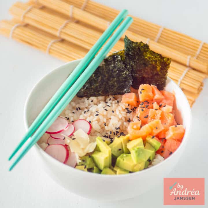 A square picture with a white bowl filled with sushi rice, avocado, radishes, smoked salmon, nori sheet, sushi rice