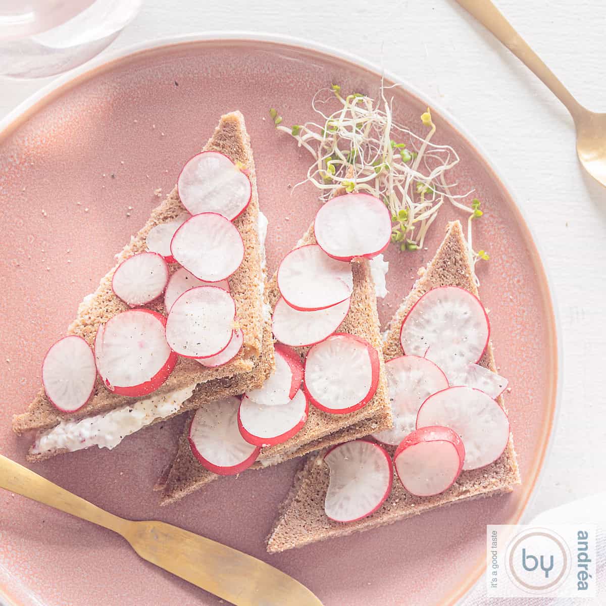 Een vierkante foto van een roggebrood-theesandwich met radijsspread