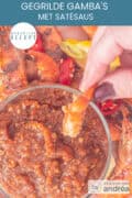 Een glas gevuld met satésaus waarin een garnaal wordt gedipt. Een tekst: makkelijk recept, gegrilde gamba's met satésaus