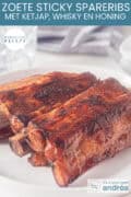 Een deel van een bord met sticky spareribs erop. Een tekst: makkelijk recept, zoete sticky spareribs met ketjap, whisky en honing