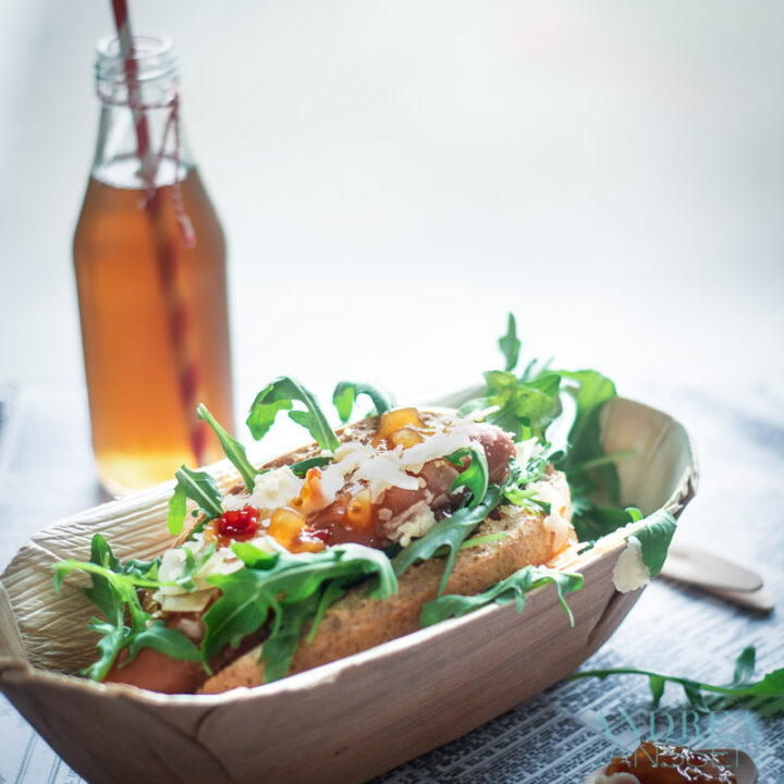 een bamboe bakje met een Hot dog de luxe en een flesje prik