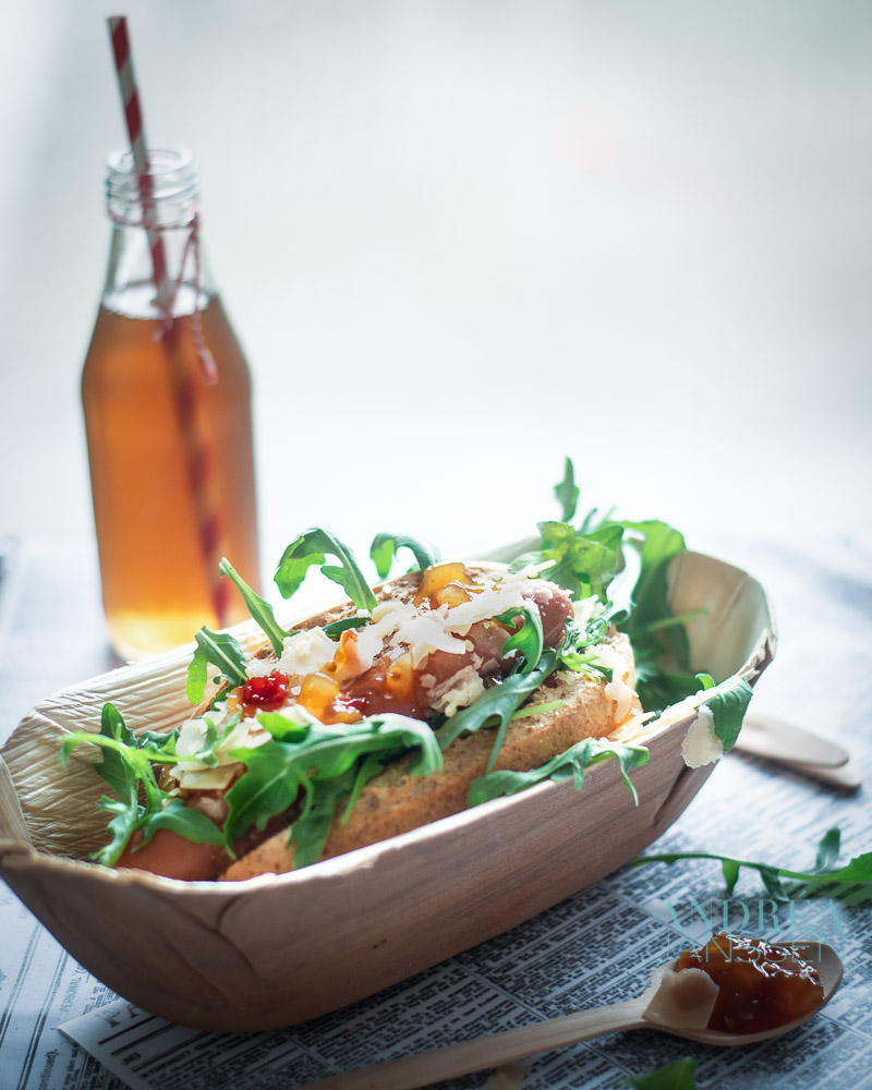 een bamboe bakje met een Hot dog de luxe en een flesje prik